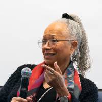 woman seated holds microphone